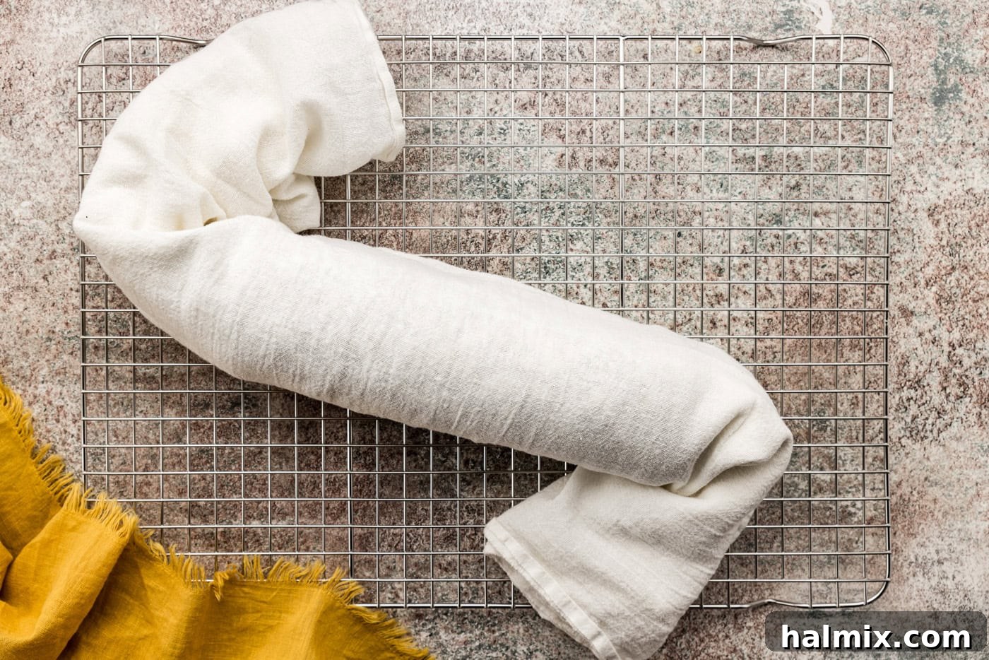 The pumpkin cake roll, perfectly wrapped and cooling in a kitchen towel on a wire rack, patiently waiting for its creamy filling.