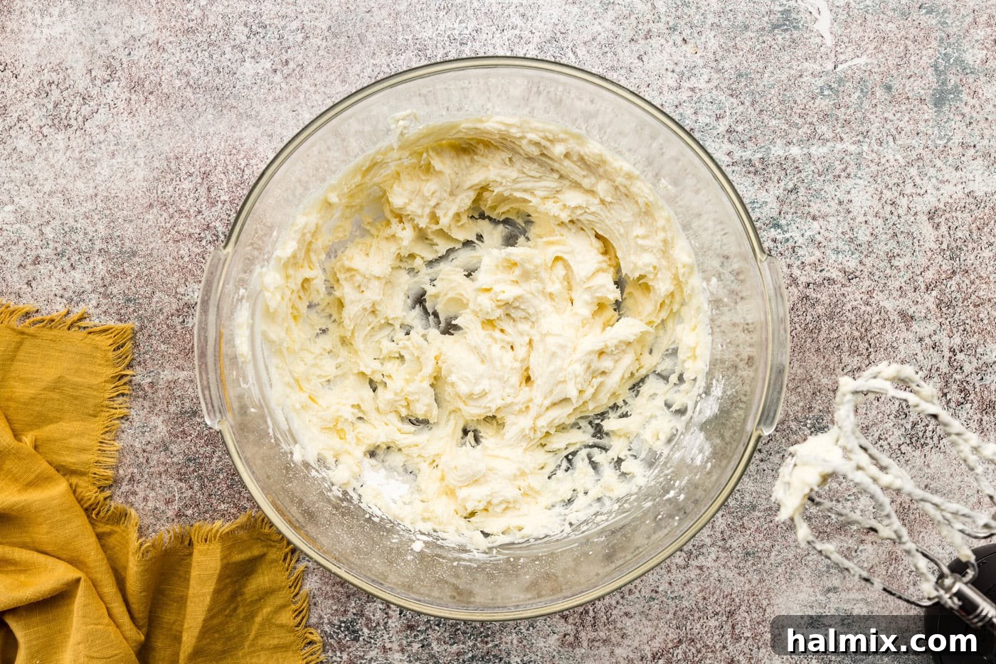 Smooth and fluffy cream cheese frosting prepared in a mixing bowl, awaiting its role in the pumpkin cake roll.