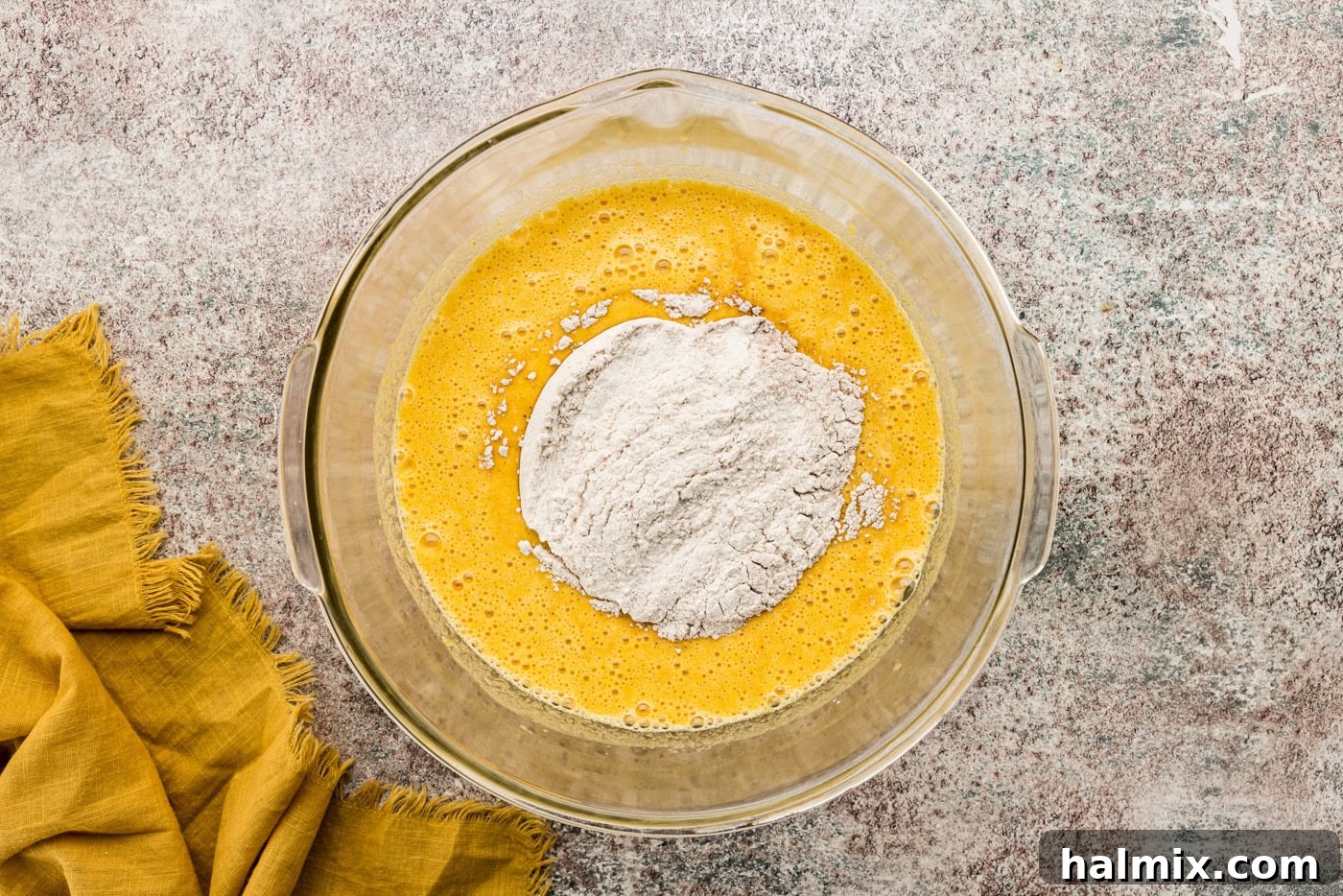 The combined flour mixture being carefully folded into the moist pumpkin batter in a mixing bowl, ensuring even blending without overmixing.