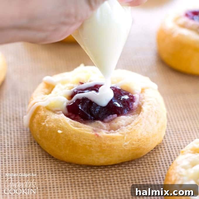 Chef drizzling sweet vanilla icing over freshly baked Cranberry Cream Cheese Pastries.