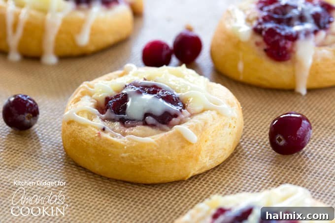 Warm Cranberry Cream Cheese Pastries topped with a delicate sugar glaze, cooling on a baking sheet.