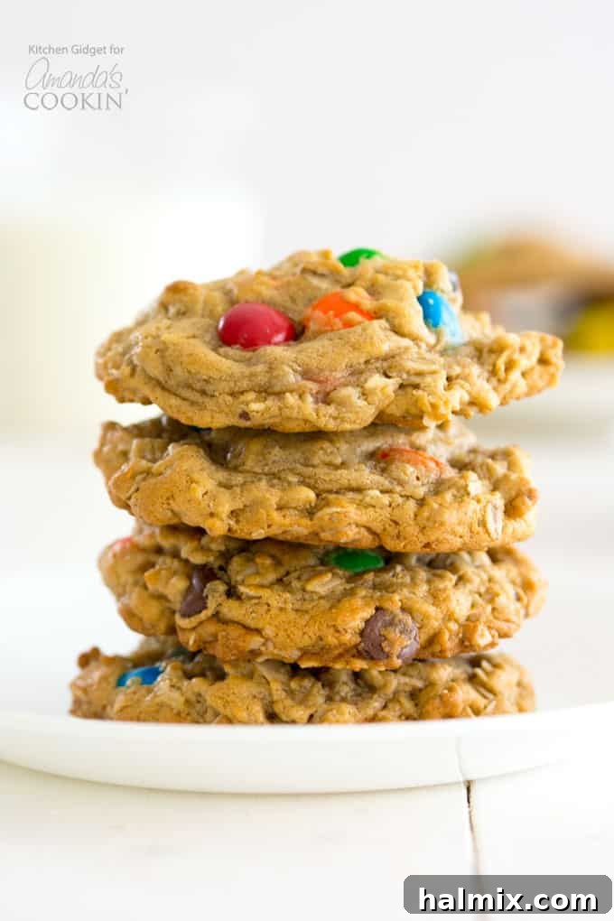 Monster Cookies: Irresistible peanut butter and oatmeal cookies packed with chocolate chips and colorful M&M's – a fun and easy recipe for everyone! #monstercookies #m&ms #cookierecipes #bestdessertrecipes #chocolate #peanutbutter #peanutbuttercookies #oatmeal #oatmealcookies Stacked peanut butter and M&M's Monster Cookies, freshly baked and ready to enjoy.