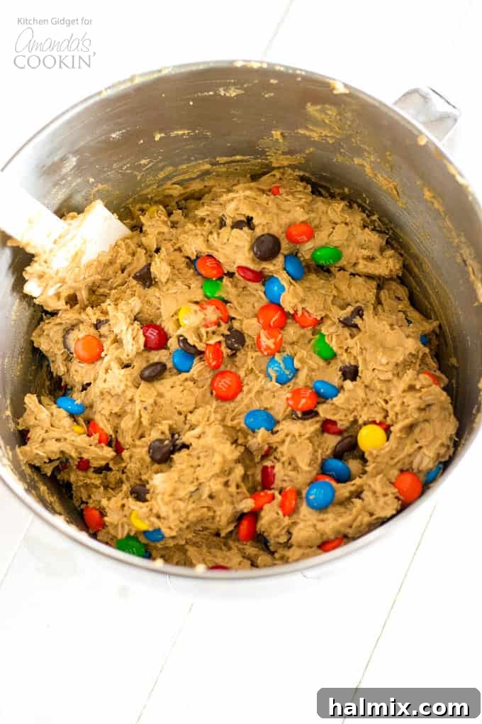 Monster Cookies: Irresistible peanut butter and oatmeal cookies packed with chocolate chips and colorful M&M's – a fun and easy recipe for everyone! #monstercookies #m&ms #cookierecipes #bestdessertrecipes #chocolate #peanutbutter #peanutbuttercookies #oatmeal #oatmealcookies How to make Monster Cookies - ingredients in mixing bowl, showing the rich texture before baking