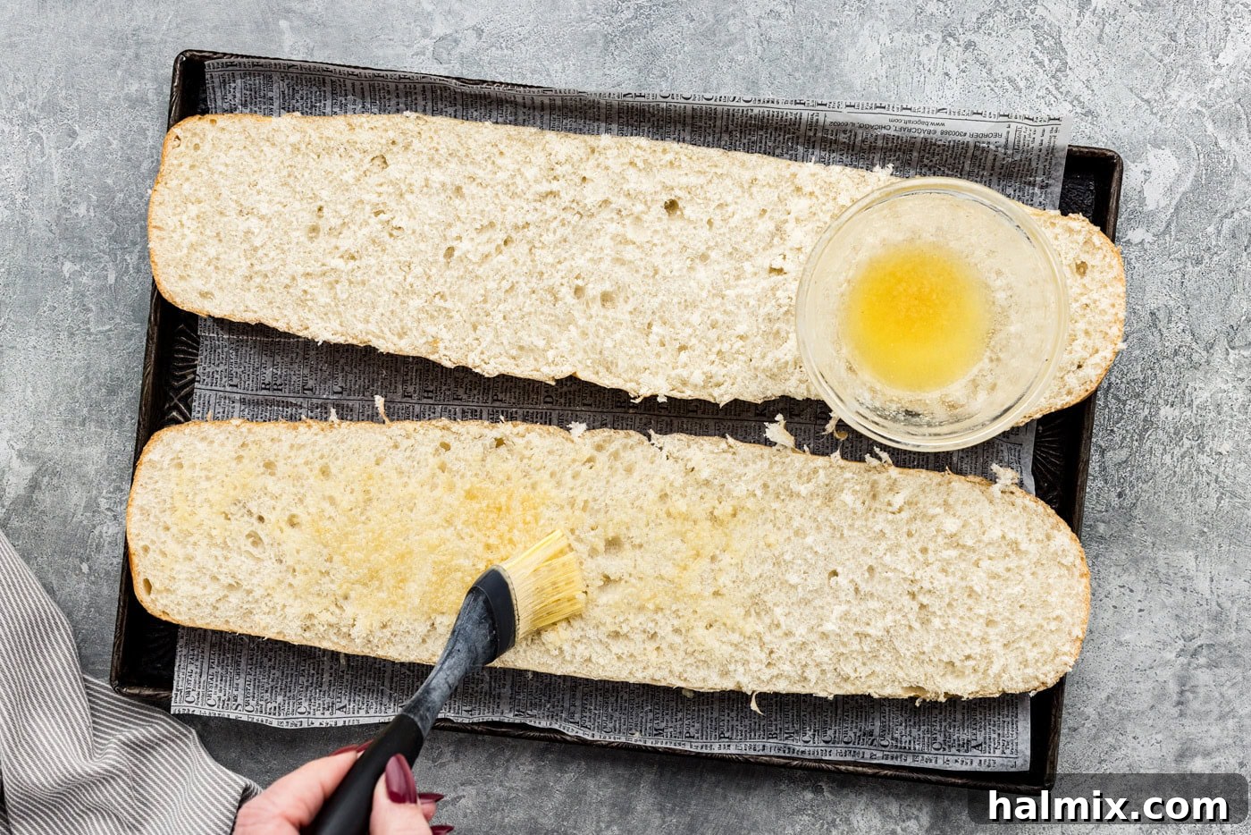 Basting garlic butter on halves of French bread