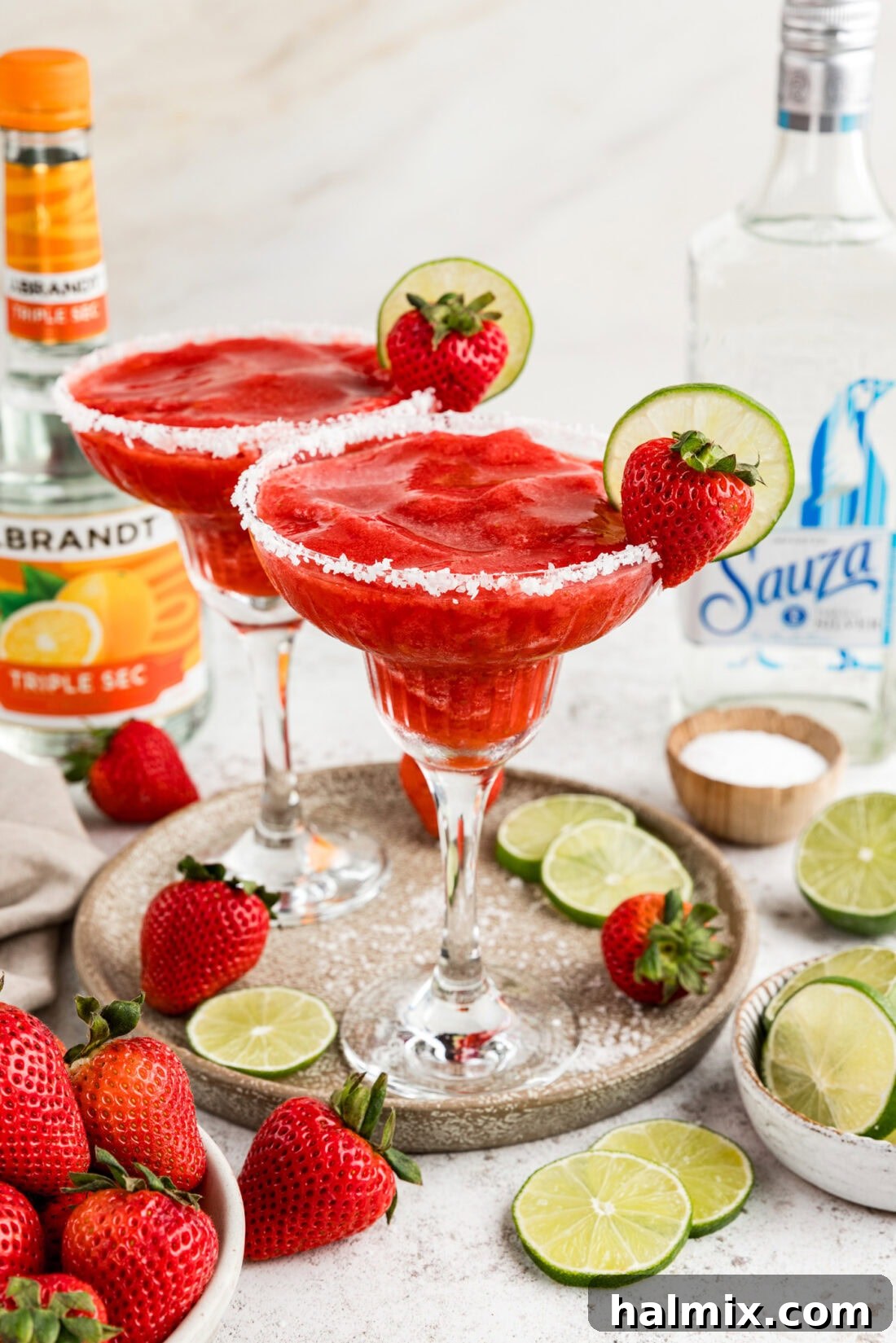 Two Strawberry Margaritas on a serving platter surrounded by limes and strawberries, evoking a fresh, vibrant feel