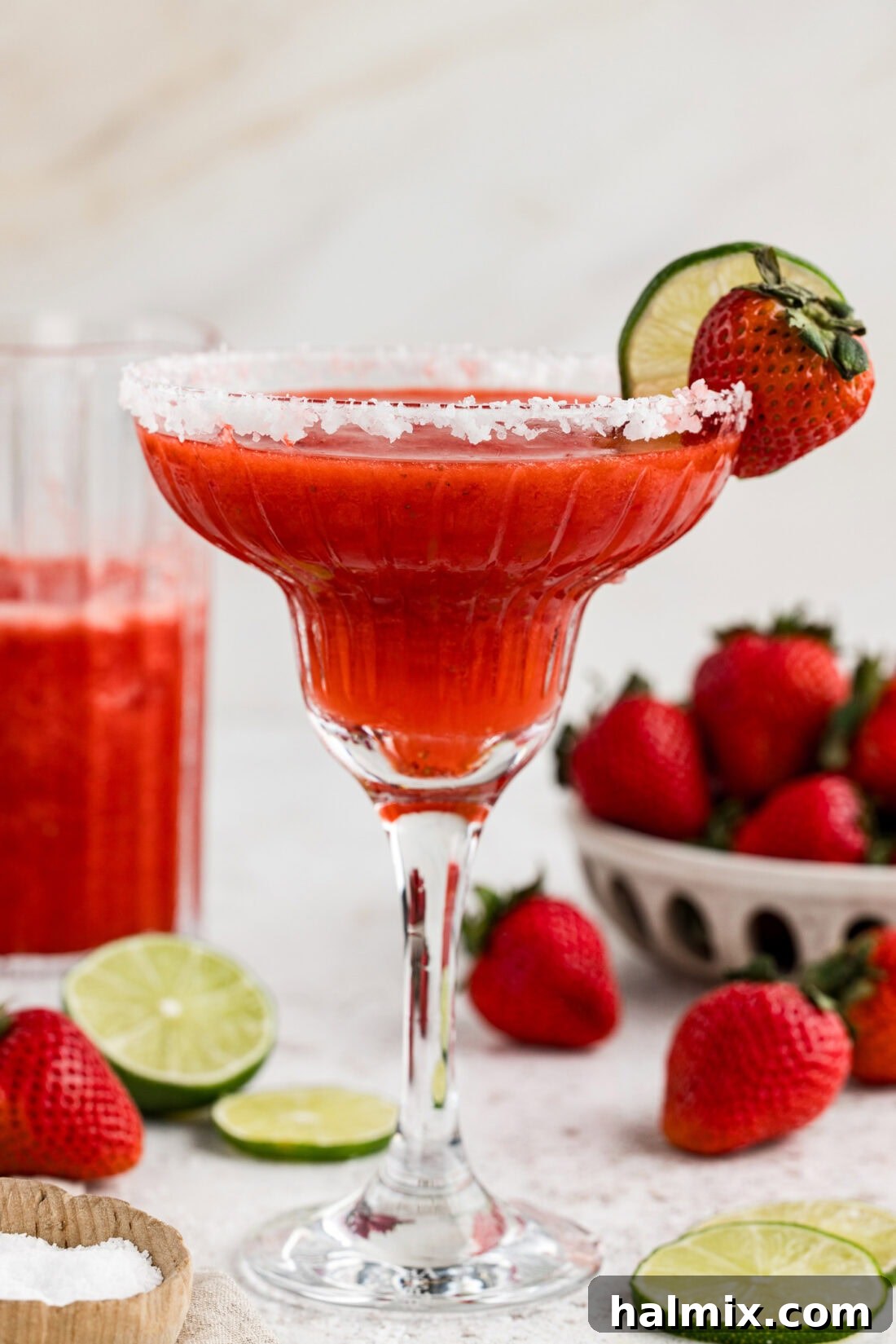 Side view of a vibrant Frozen Strawberry Margarita garnished with a lime wheel and strawberry