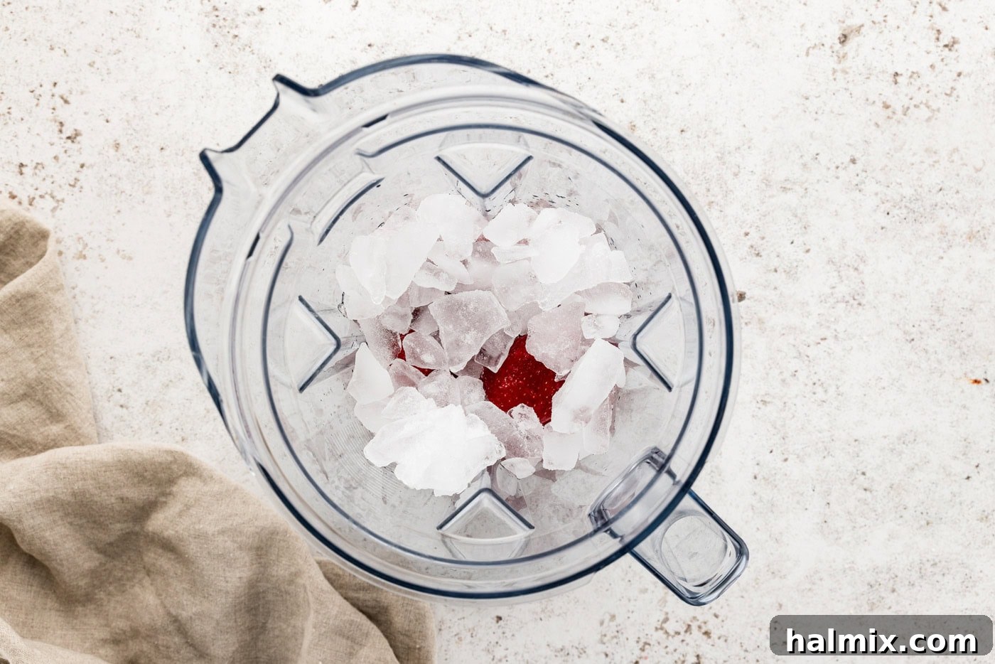 Ice on top of strawberries in a blender, ready for blending