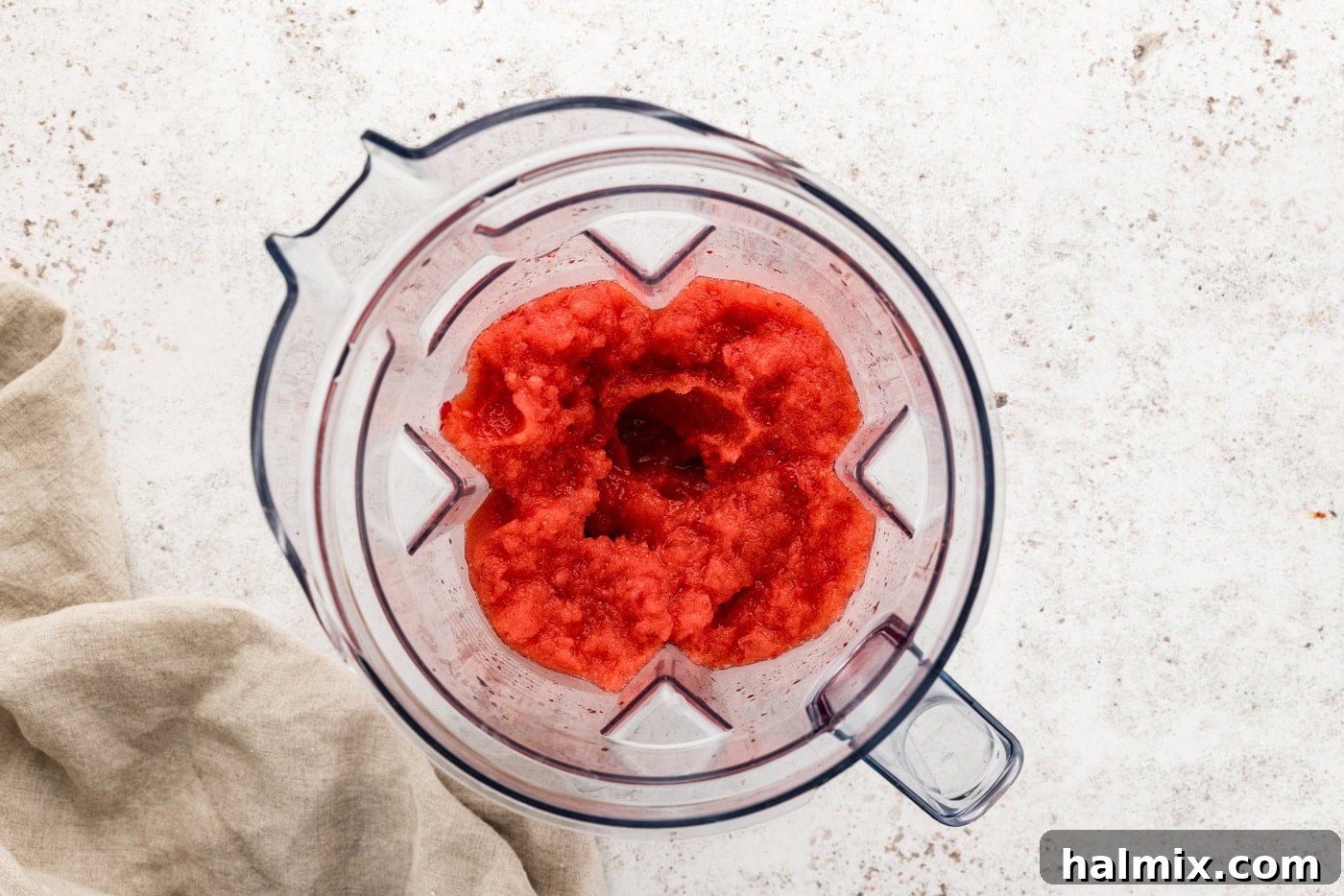 Overhead shot of frozen strawberry margarita slush in a blender, showing its smooth texture