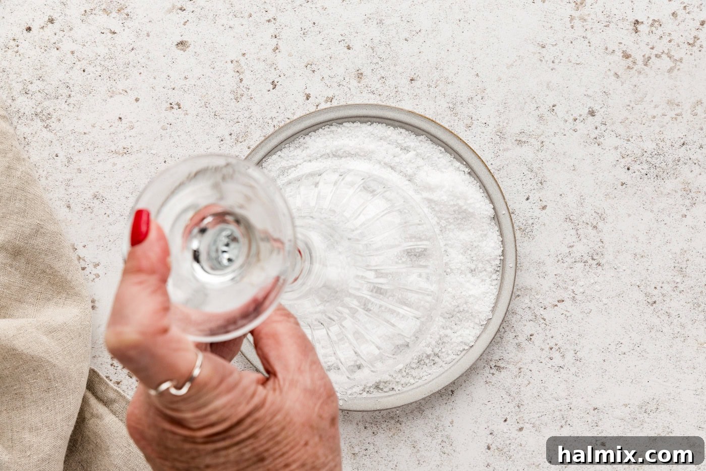 Hand holding a martini glass upside down and dipping its rim into salt