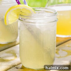 Mason jar glass of Lynchburg lemonade with a straw and lemon wedge garnish, showing a perfectly mixed cocktail.