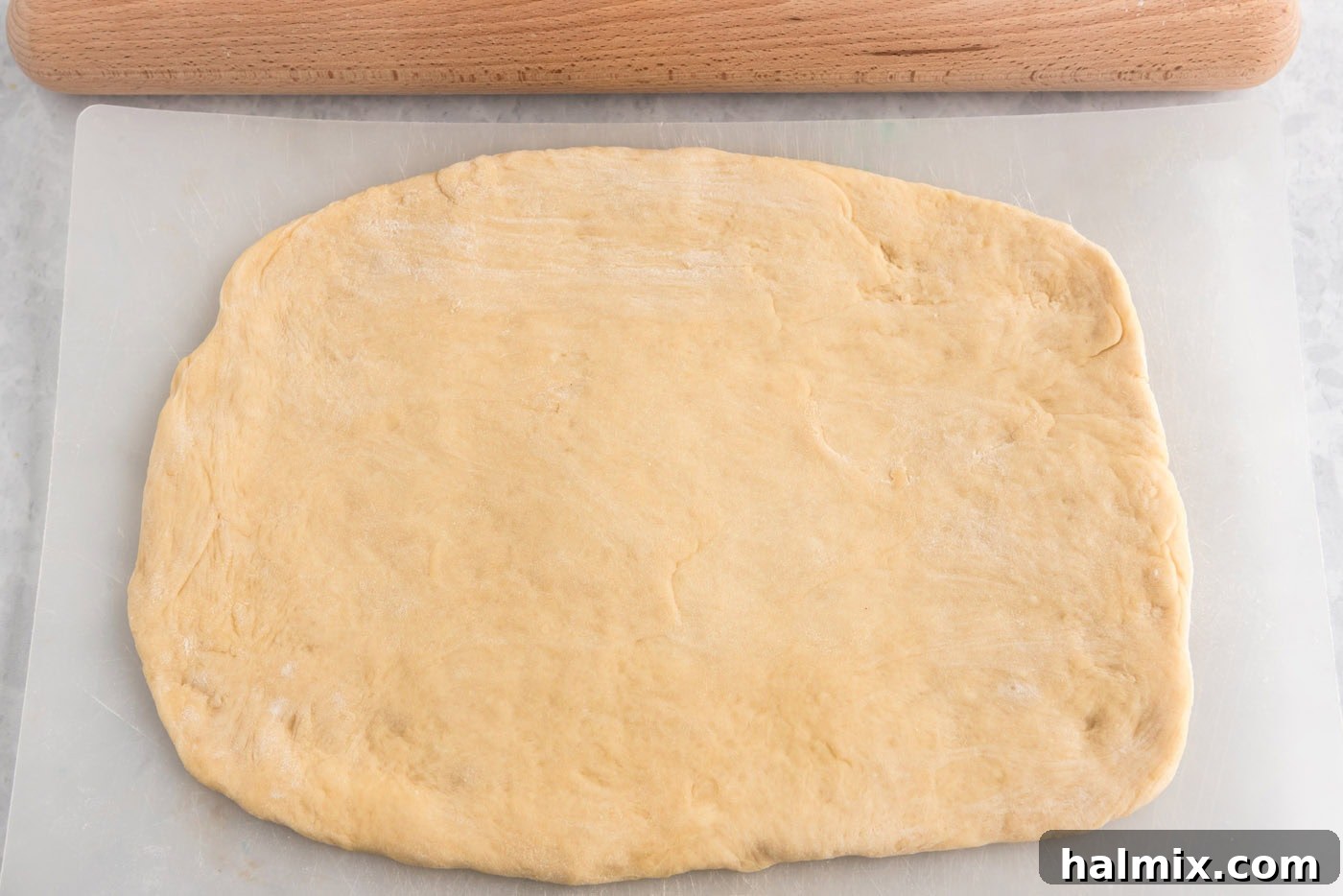 Dough rolled out into a large rectangle on a flat surface.
