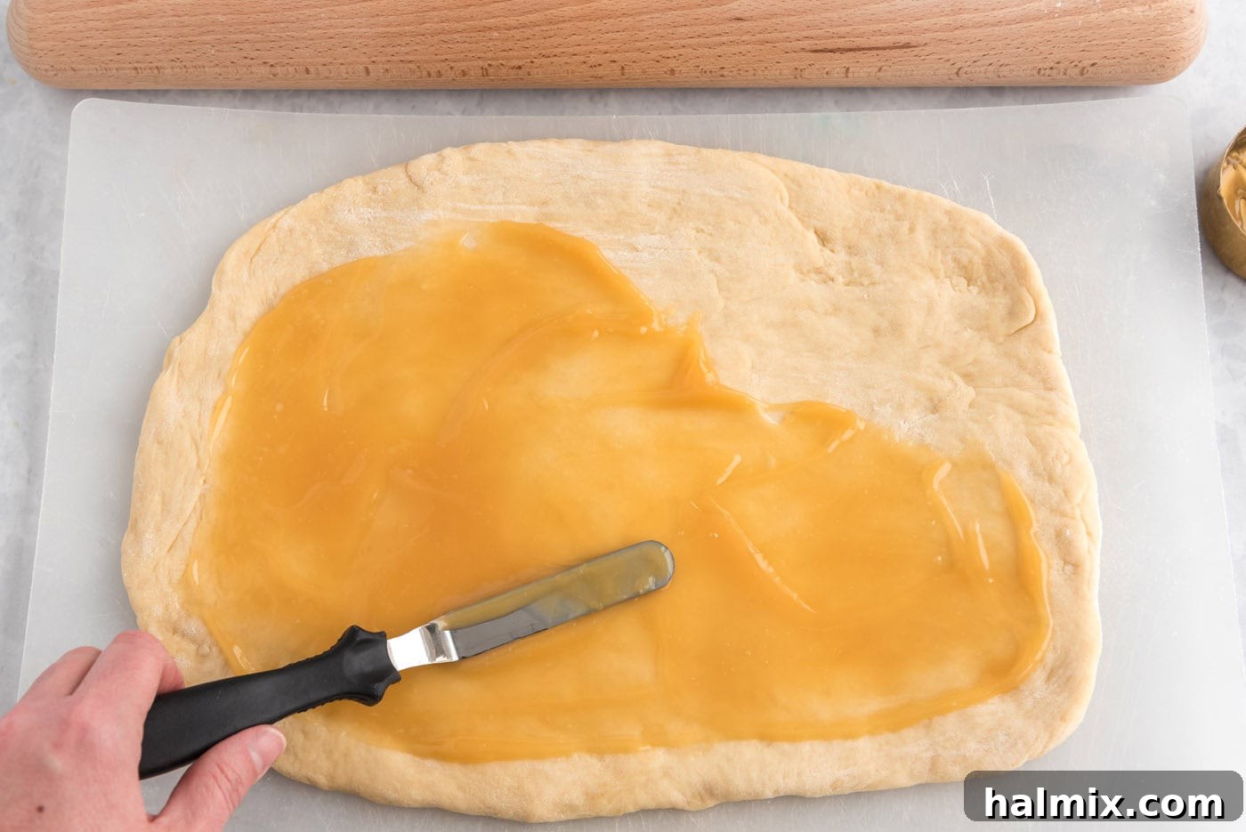 Lemon curd evenly spread over the rolled-out dough.