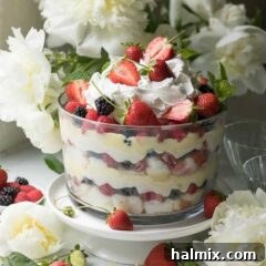 A delightful berry trifle with flowers in the background, signaling a fresh summer treat.