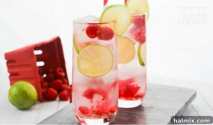 Four Raspberry Gin Rickeys in elegant glasses with lime wedges and fresh raspberries, ready for a summer party.