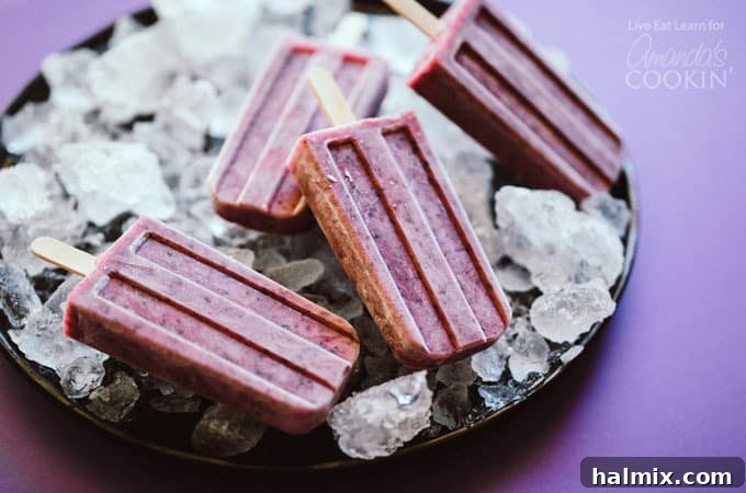 Deliciously healthy Blueberry Cheesecake Popsicles, a must-try summer dessert Blueberry Cheesecake Popsicles beautifully arranged on a bed of ice