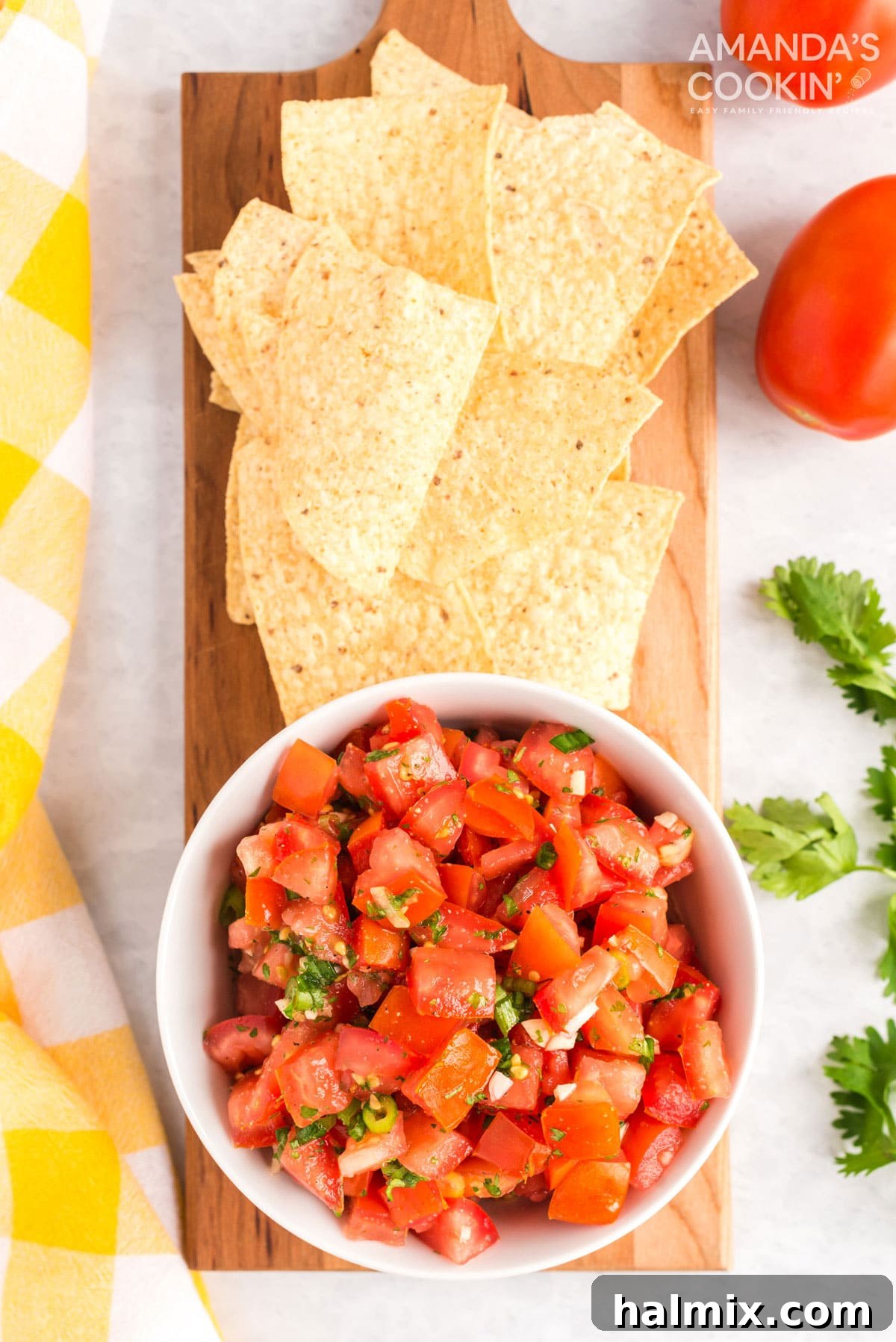 A beautiful bowl of homemade Pico de Gallo sits on a rustic cutting board, surrounded by golden tortilla chips, inviting a fresh and flavorful snack.
