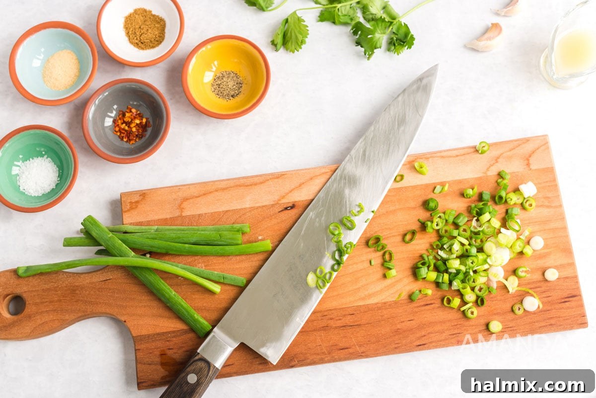 Finely chopped green onions and a knife on a wooden cutting board, highlighting the fresh ingredients for homemade salsa.
