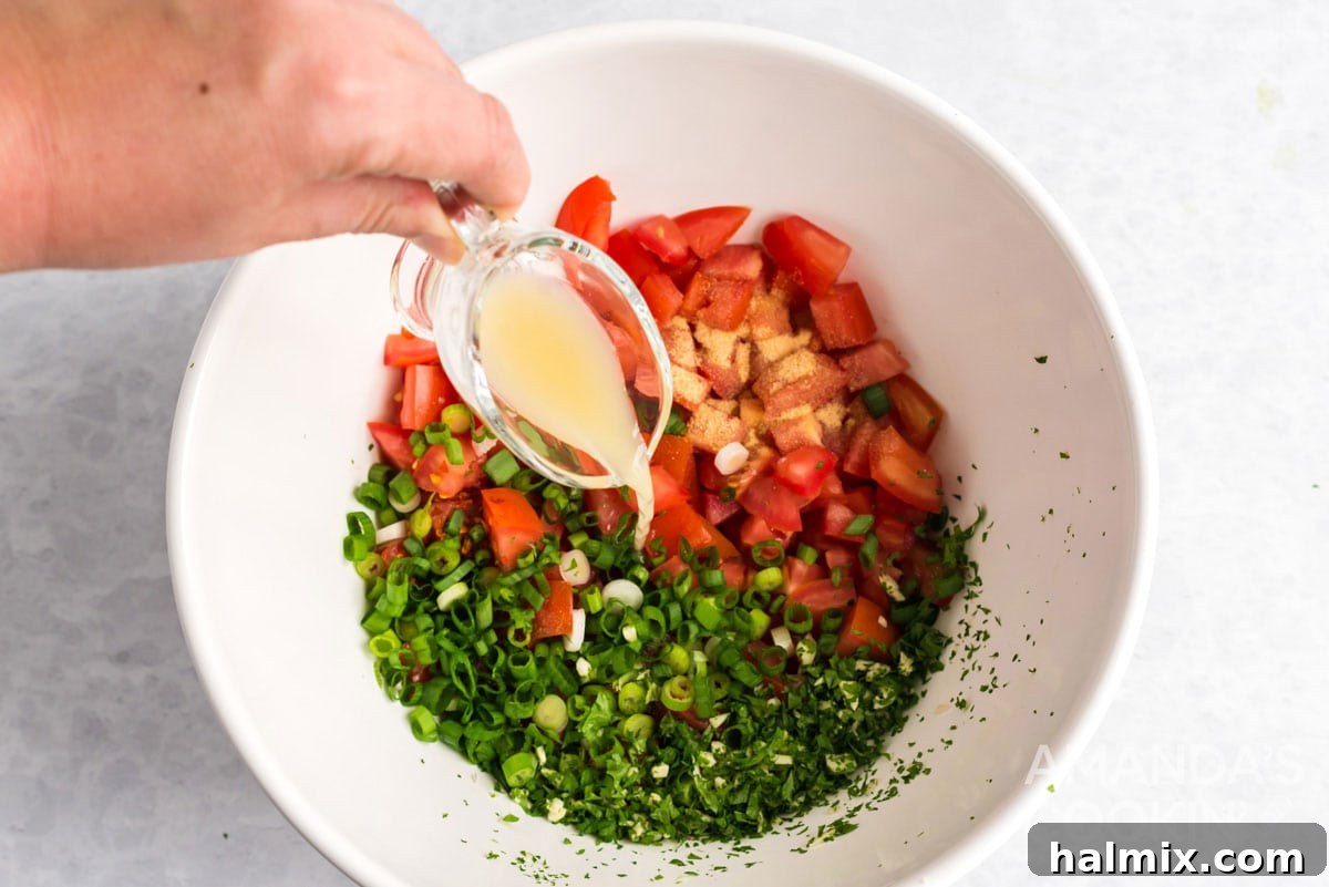 Pouring fresh lime juice into a bowl filled with chopped tomatoes, cilantro, and other ingredients for Salsa Fresca, adding a tangy finish.