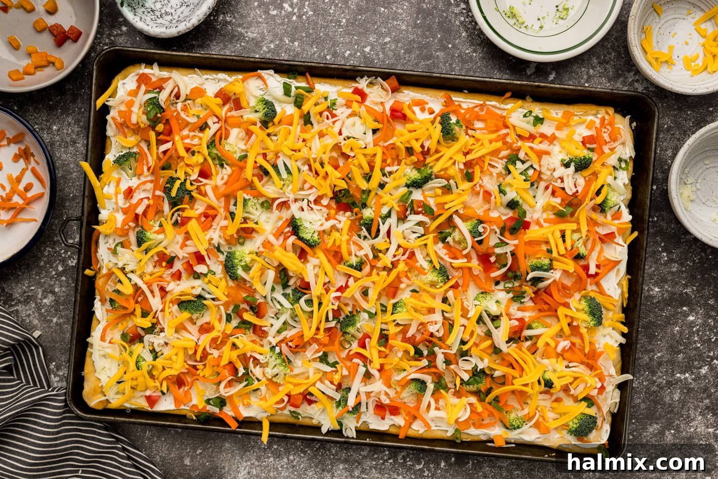 shredded cheese and vegetables on top of cream cheese and crescent dough pizza