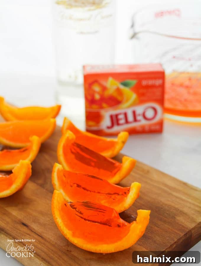 Bright orange jello shots nestled in orange rinds, ready to serve at a party.