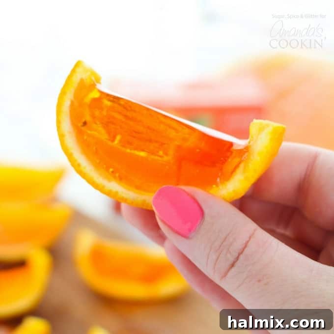 Delicious orange jello shots artfully arranged in their natural orange rinds on a rustic wooden surface.