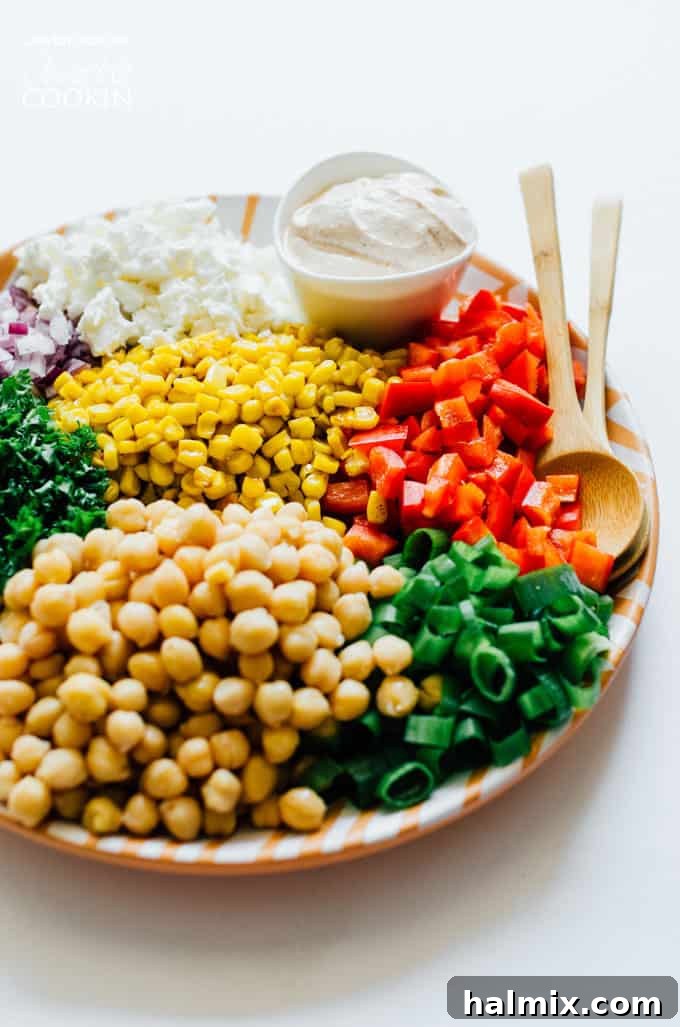 This Sweetcorn and Chickpea Salad recipe is quick to whip up and so tasty. It's filled with healthy proteins and packed with flavor! Fresh ingredients for sweet corn and chickpea salad arranged on a white plate