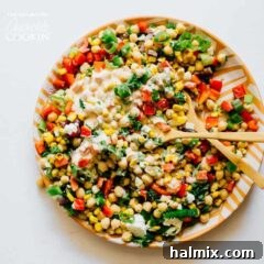 Colorful sweet corn and chickpea salad served on a plate with two spoons