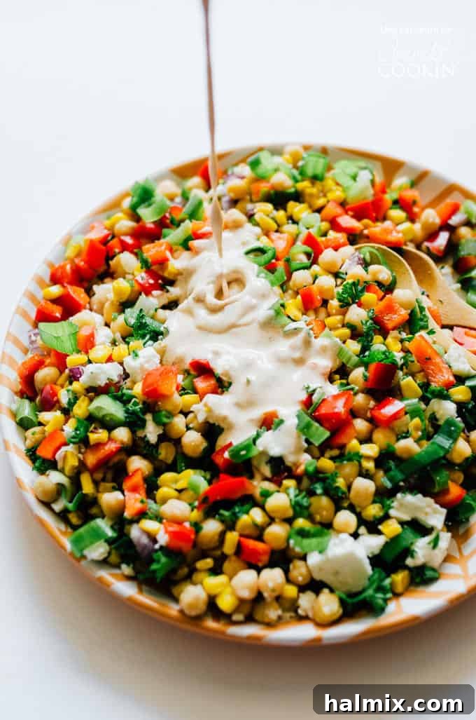 This Sweetcorn and Chickpea Salad recipe is quick to whip up and so tasty. It's filled with healthy proteins and packed with flavor! Close-up of sweet corn and chickpea salad with a drizzle of creamy dressing