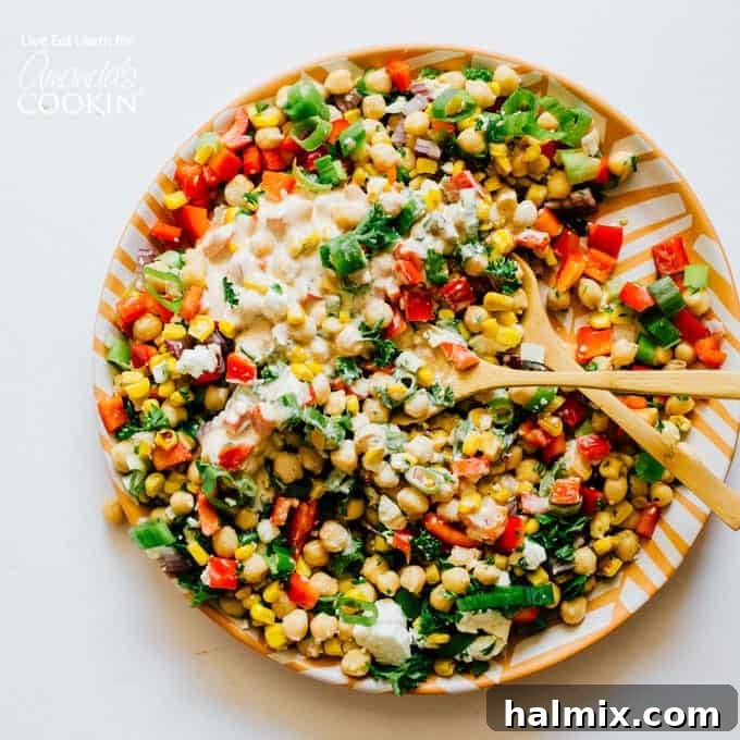 This Sweetcorn and Chickpea Salad recipe is quick to whip up and so tasty. It's filled with healthy proteins and packed with flavor! Colorful sweet corn and chickpea salad served on a plate with two spoons