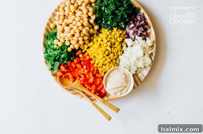 This Sweetcorn and Chickpea Salad recipe is quick to whip up and so tasty. It's filled with healthy proteins and packed with flavor! Close up of a vibrant chickpea salad with sweet corn and fresh vegetables on a plate