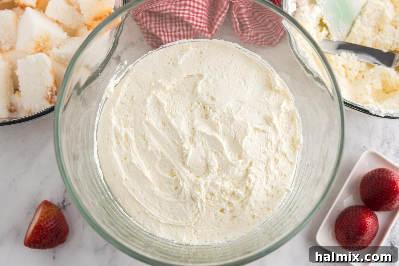 layer of whipped cream cheese on top of angel food cake in a trifle dish
