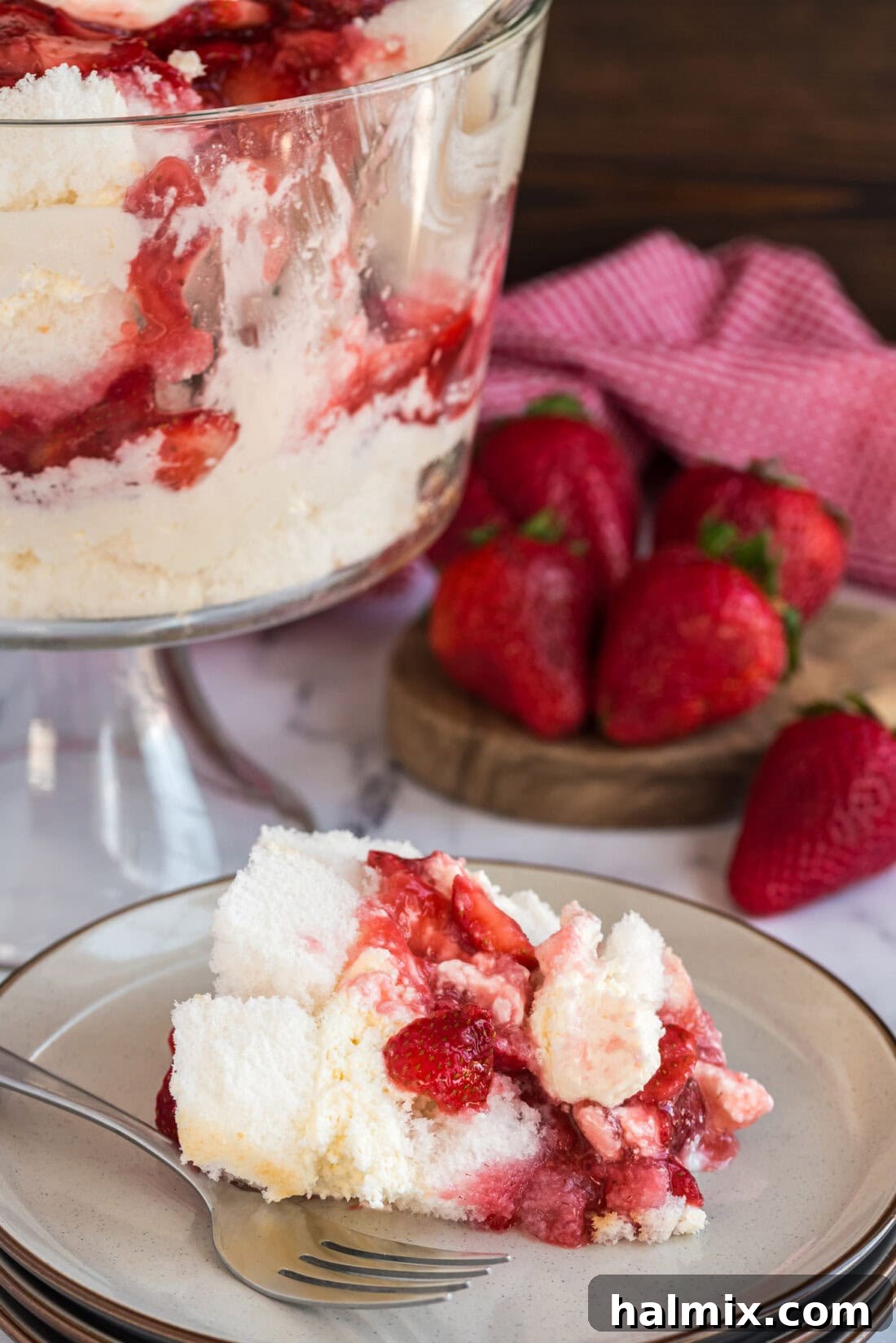 Serving of Strawberry Shortcake Trifle on a plate with the remaining trifle in the background