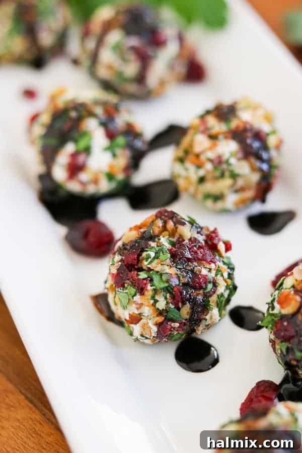 Delicate cranberry pecan goat cheese bites, elegantly arranged and garnished with fresh rosemary, offering a sophisticated appetizer.