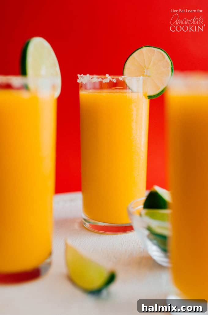 Three glasses full of mango margarita slush with a lime garnish