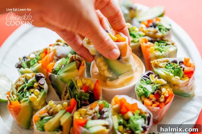 Mexican style summer rolls are a delicious and healthy addition to your snacking routine, especially with the smoky chipotle dip! Close-up shot of a Mexican style summer roll being carefully dipped into a small, elegant bowl of the homemade smoky chipotle sauce. The vibrant colors of the roll's filling are visible through the translucent wrapper.