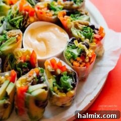 A close-up shot of Mexican style summer rolls arranged beautifully around a central bowl of smoky chipotle dipping sauce.