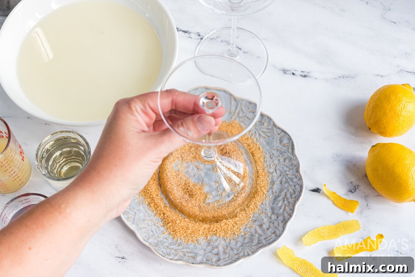 Dipping a martini glass into sanding sugar to create a sugared rim for a Lemon Drop cocktail.