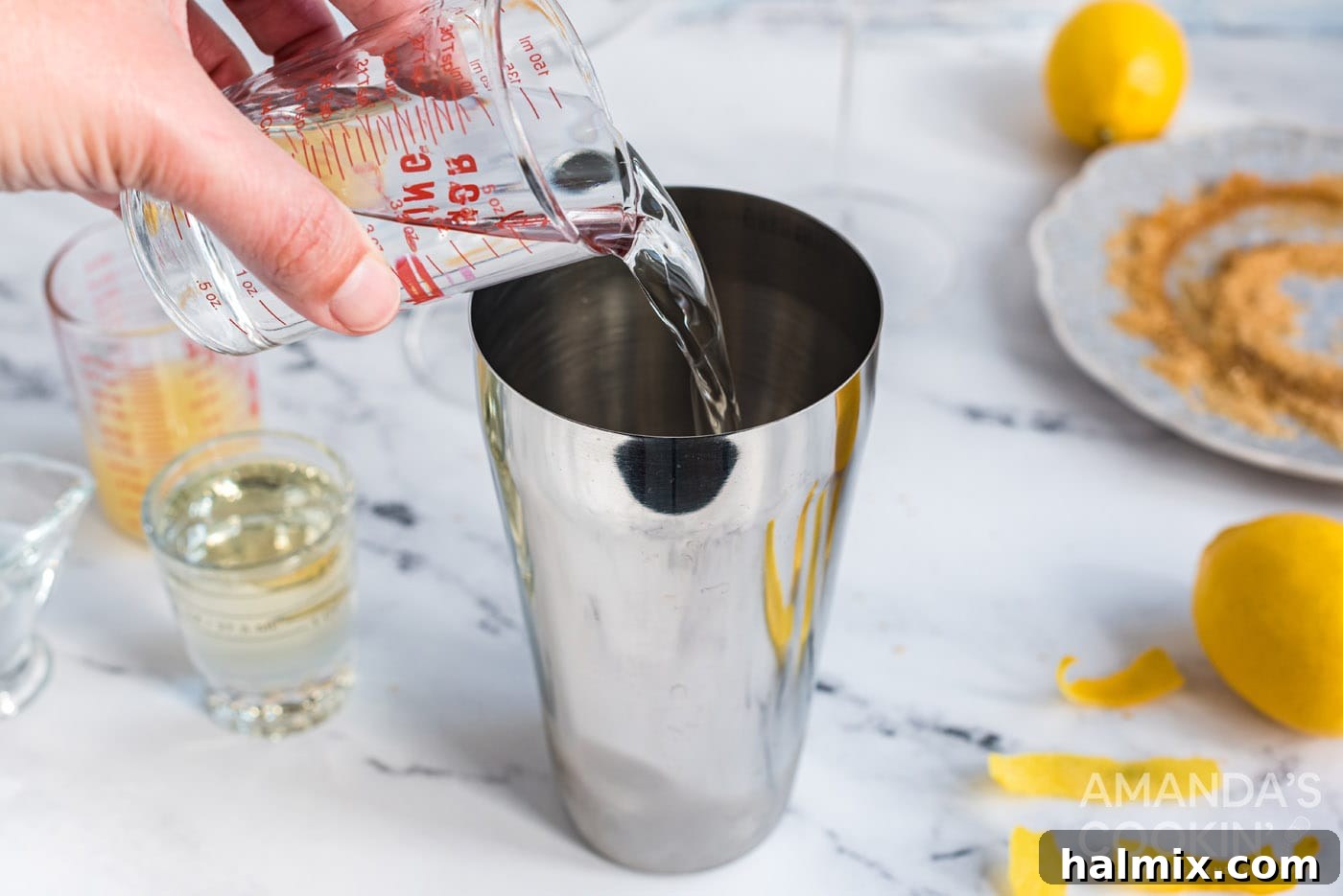 Pouring vodka into a cocktail shaker filled with ice, a key step in making a Lemon Drop.
