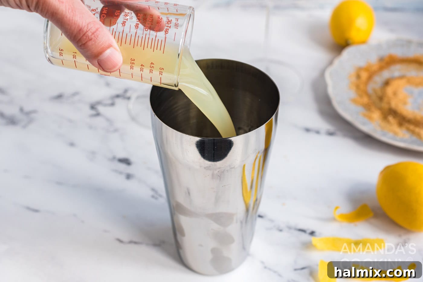 Adding fresh lemon juice to a cocktail shaker, ensuring a vibrant and tart Lemon Drop cocktail.