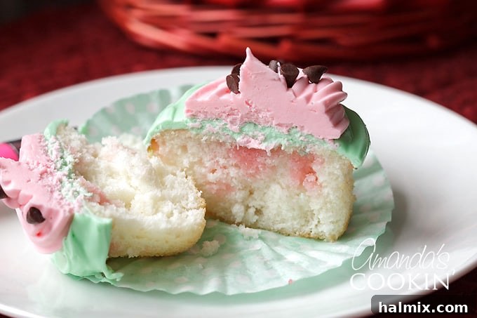 Watermelon Poke Cupcake Cross-section A watermelon poke cupcake cut in half, showcasing the vibrant colors and chocolate chip 'seeds'