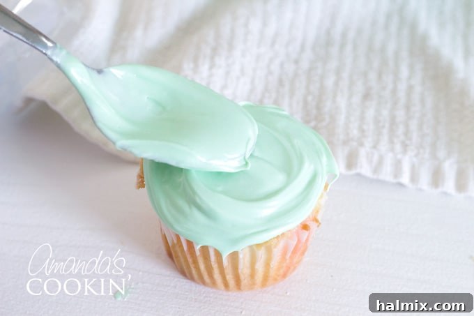 Watermelon Burst Cupcakes 6 Spreading a thin layer of green frosting on a cupcake