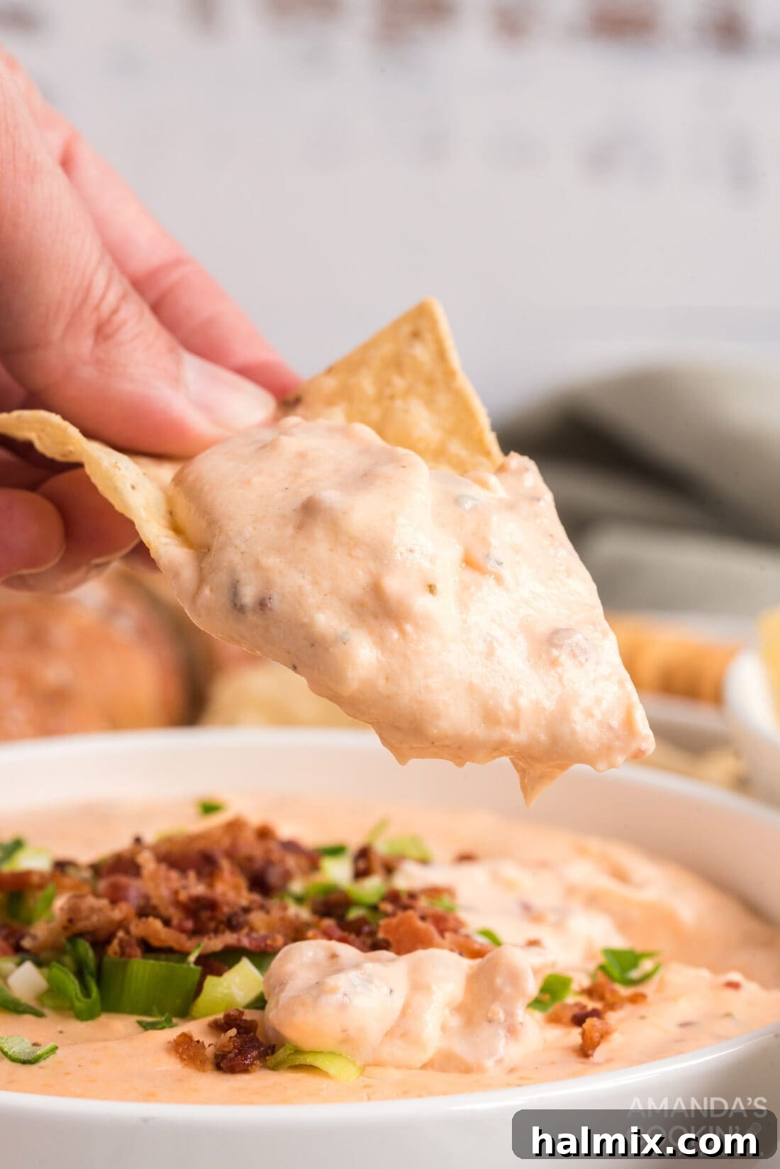 A tortilla chip generously dipped into the Crockpot Cheese Dip, showing the rich, creamy texture.