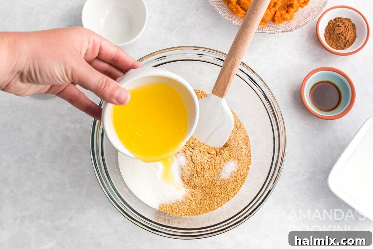 Effortless Pumpkin Cheesecake 3 Melted butter being added to a bowl of graham cracker crumbs, sugar, and salt for the cheesecake crust.