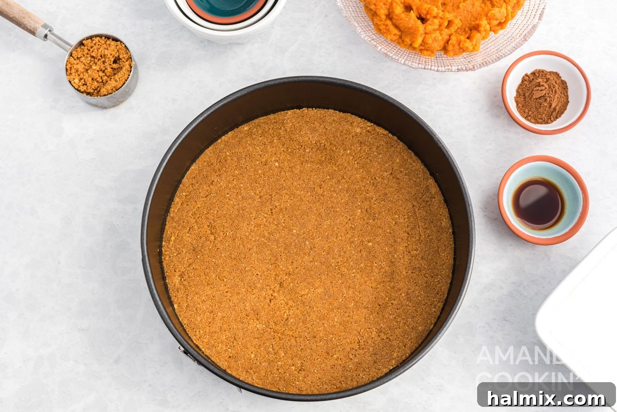 Effortless Pumpkin Cheesecake 5 The graham cracker crust mixture neatly pressed into the bottom of a springform pan, chilling in the refrigerator.