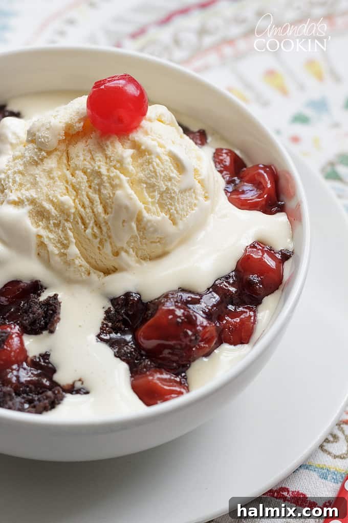 Warm crockpot chocolate cherry cobbler topped with a melting scoop of vanilla ice cream, creating a delightful contrast.