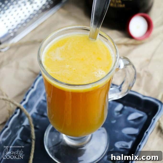 Hot buttered rum in a glass mug with a cinnamon stick.