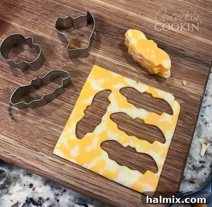 If you need Halloween food ideas for your Halloween party, be sure to check out all these sweet, savory and beverage ideas! Something for everyone. #halloweenrecipes #halloweenfoodideas #halloweenfood #halloweentreats #halloweenpartyfood #mummycookies #mozarellaeyeballs #spidertacodip #spidercookies #ricekrispypumpkins #ricekrispymonsters #dipinapumpkin #halloweenparty Close-up of Halloween-shaped cookie cutter cheese