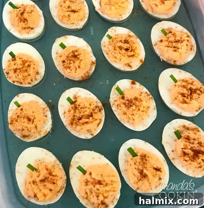 If you need Halloween food ideas for your Halloween party, be sure to check out all these sweet, savory and beverage ideas! Something for everyone. #halloweenrecipes #halloweenfoodideas #halloweenfood #halloweentreats #halloweenpartyfood #mummycookies #mozarellaeyeballs #spidertacodip #spidercookies #ricekrispypumpkins #ricekrispymonsters #dipinapumpkin #halloweenparty Pumpkin-shaped deviled eggs with paprika and chives