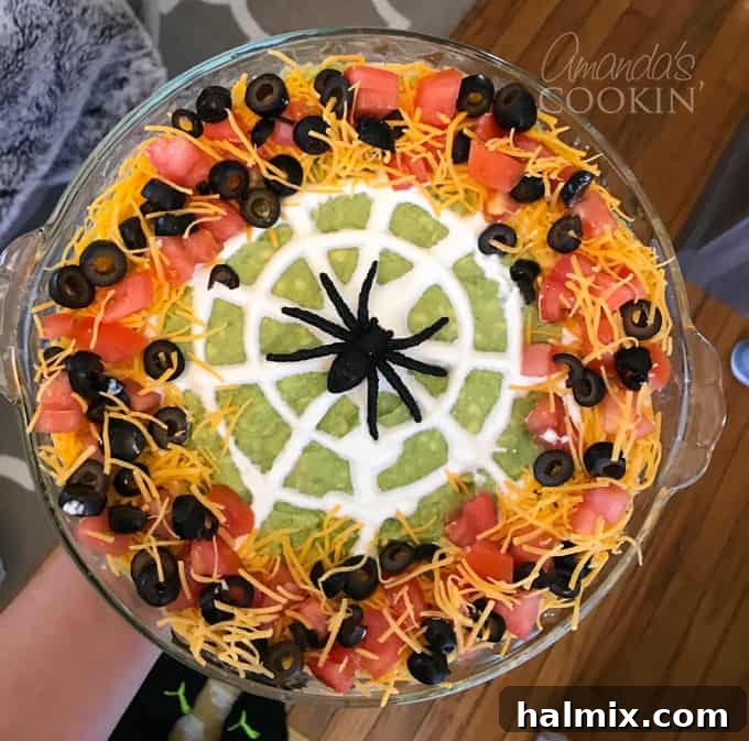 If you need Halloween food ideas for your Halloween party, be sure to check out all these sweet, savory and beverage ideas! Something for everyone. #halloweenrecipes #halloweenfoodideas #halloweenfood #halloweentreats #halloweenpartyfood #mummycookies #mozarellaeyeballs #spidertacodip #spidercookies #ricekrispypumpkins #ricekrispymonsters #dipinapumpkin #halloweenparty Spider web taco dip in a serving bowl with tortilla chips