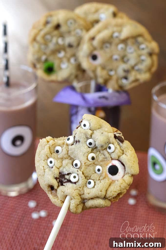 Monster Eyeball Cookie Pops, a fun Halloween treat that kids and adults will love, served with monster chocolate milk! #halloweencookies #monstercookies #eyeballcookies #chocolatechipcookies #halloweenrecipes #candyeyeballs #lollipops #cookiepop #sponsored #PourMoreMilk #MilkLife #FarmToTable #MadeLocal #Sustainable #RecipeOfTheDay #EatLocal #SimpleIngredients #MadeFresh #Foodie #GoodEats #Halloween #HalloweenRecipes #HalloweenParty #HalloweenDIY #HalloweenTreats Monster Eyeball Cookie Pop with a bite taken out, next to monster chocolate milk